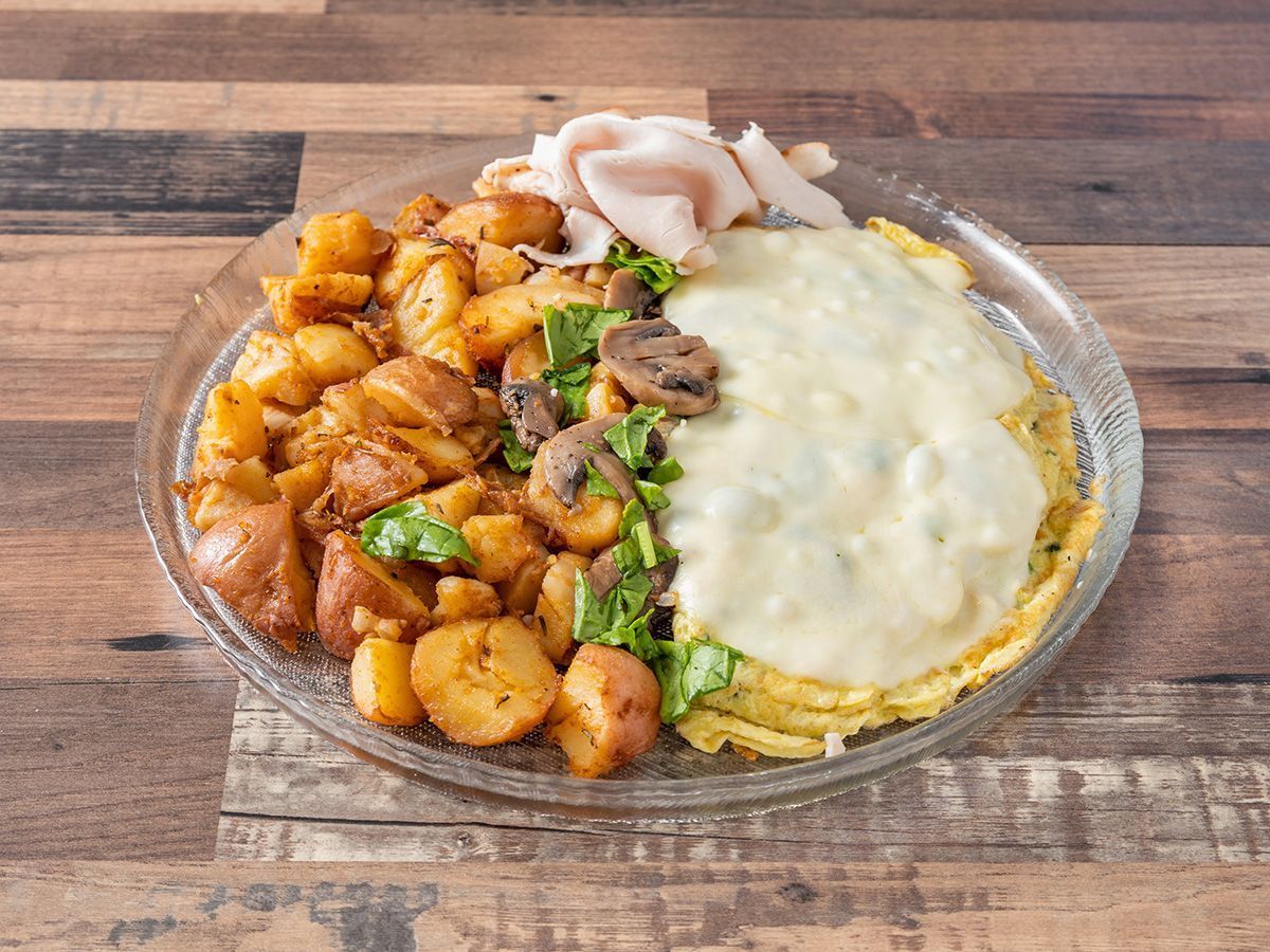 A plate of food with eggs, potatoes, mushrooms and cheese on a wooden table.