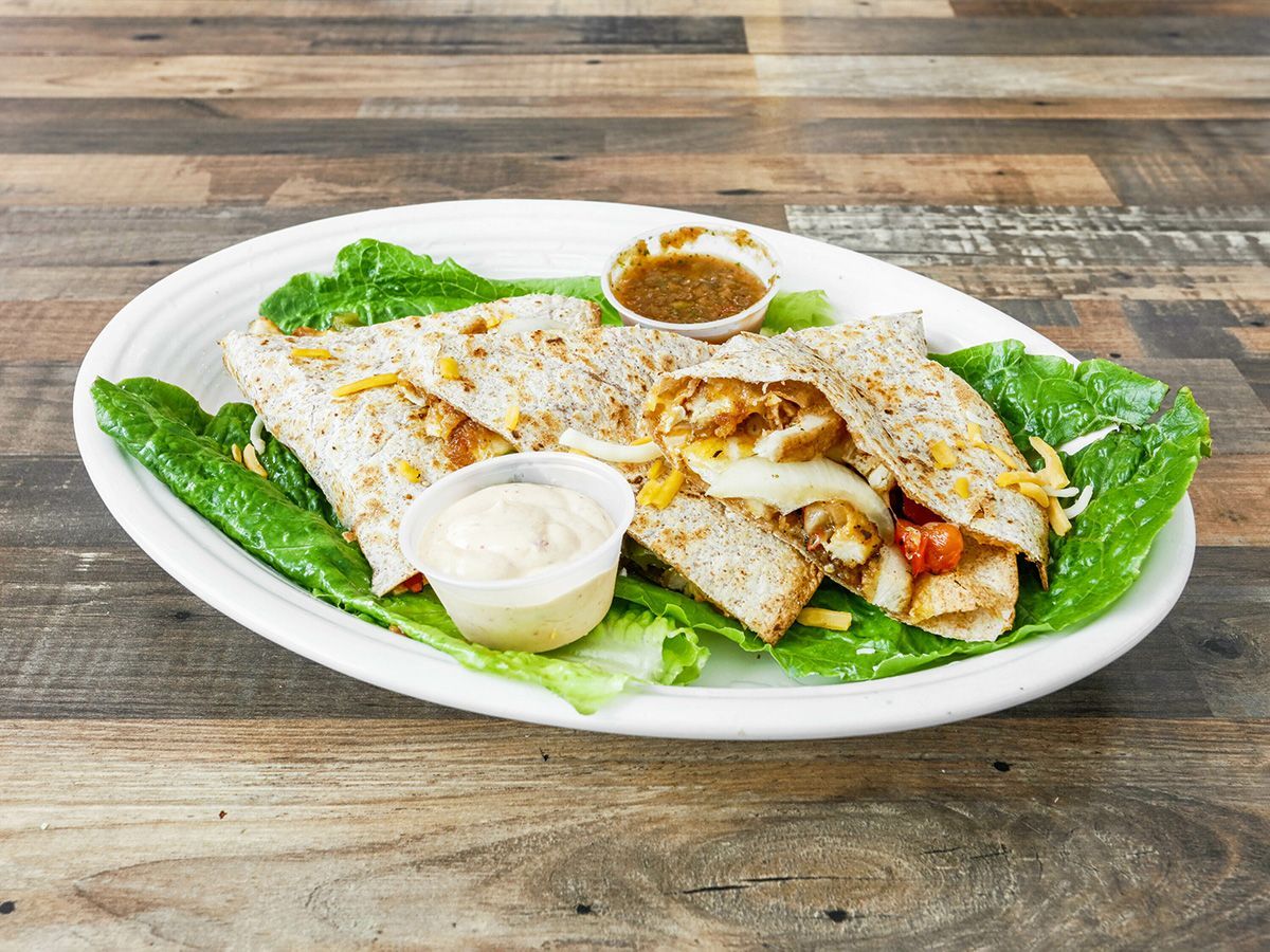 A white plate topped with quesadillas and lettuce on a wooden table.