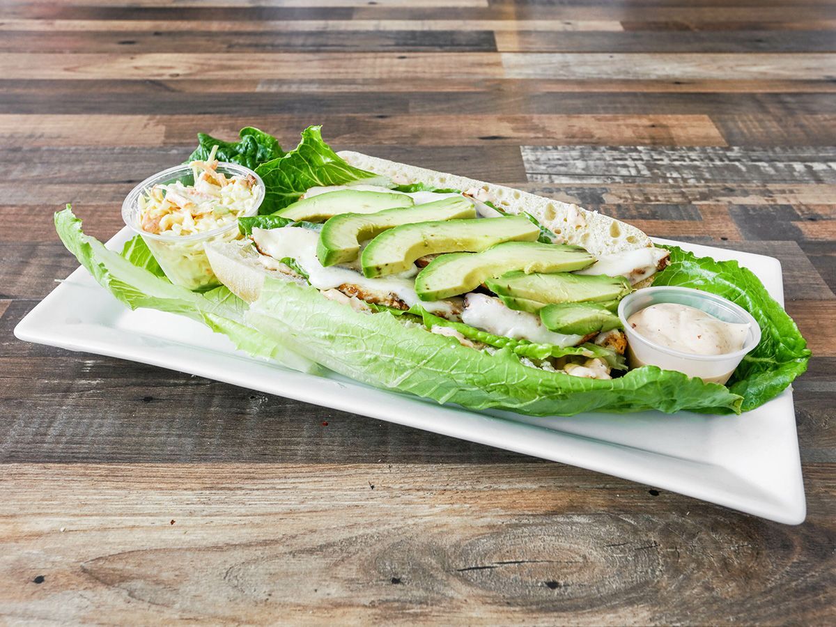 A close up of a salad on a white plate on a wooden table.