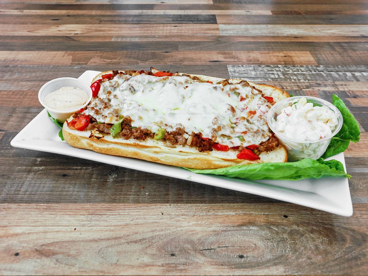 A sub sandwich on a white plate on a wooden table.