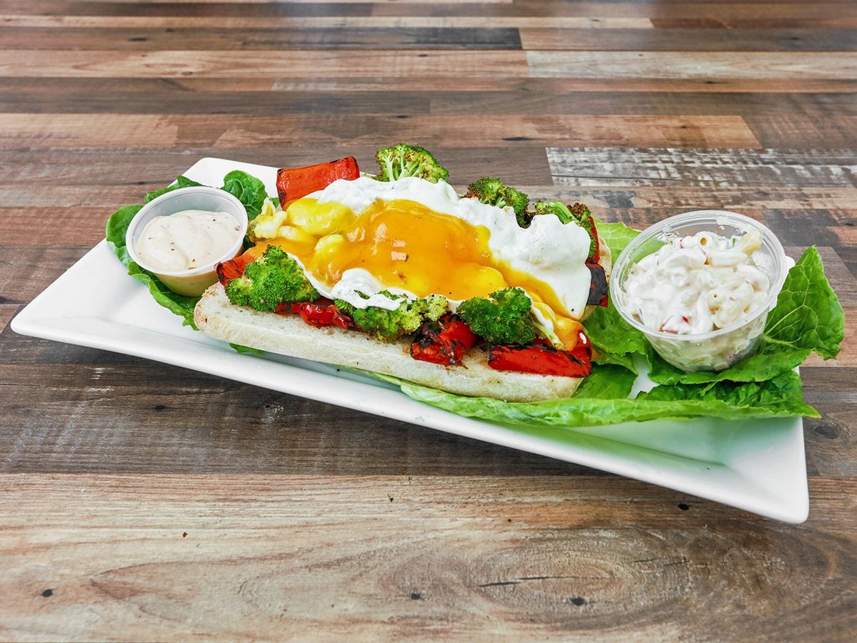 A white plate topped with a sandwich and vegetables on a wooden table.