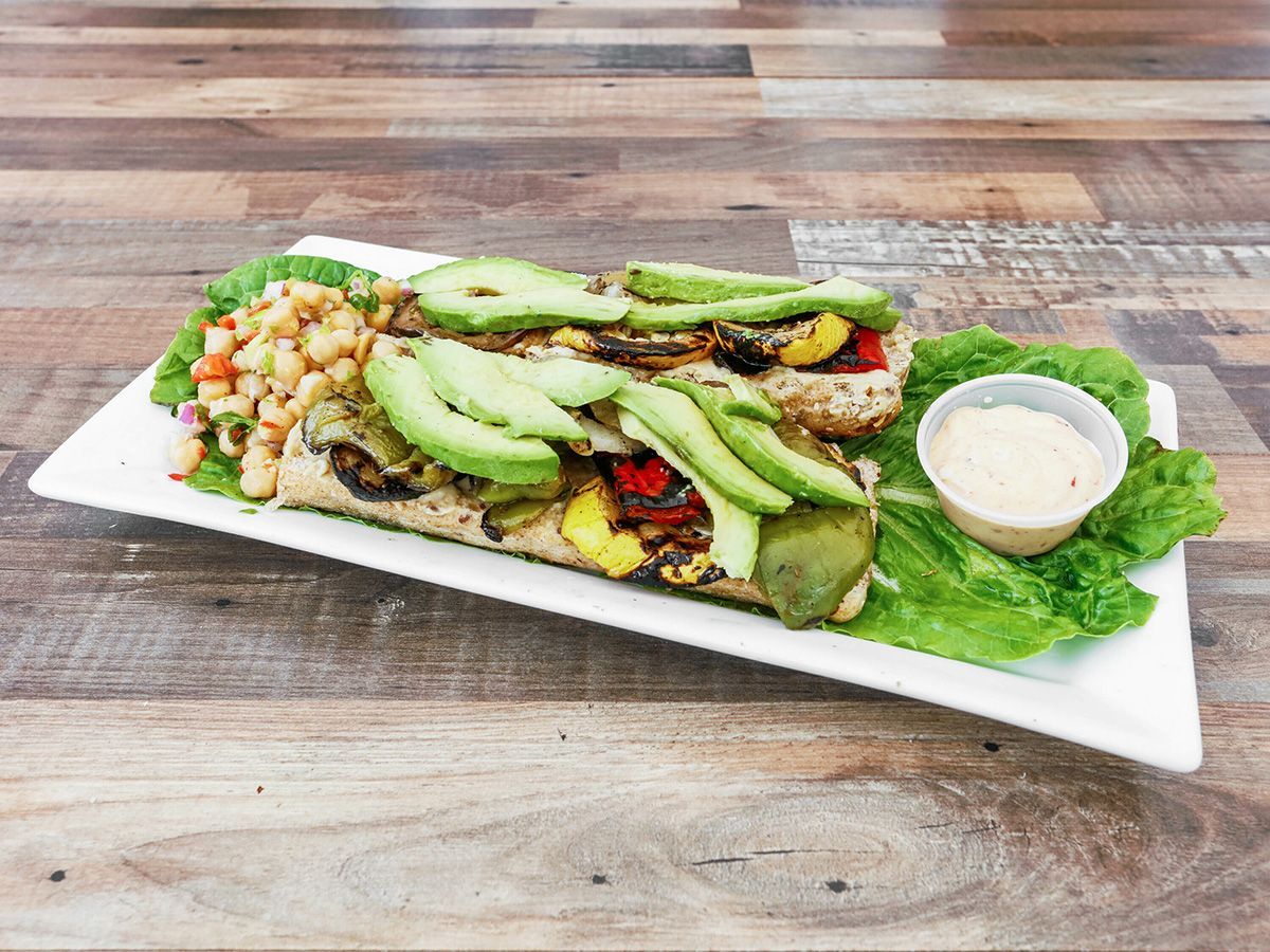 A white plate topped with a salad and avocado on a wooden table.