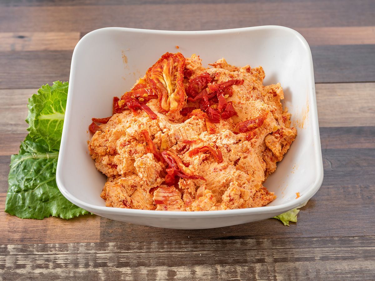 A white bowl filled with food is sitting on a wooden table.