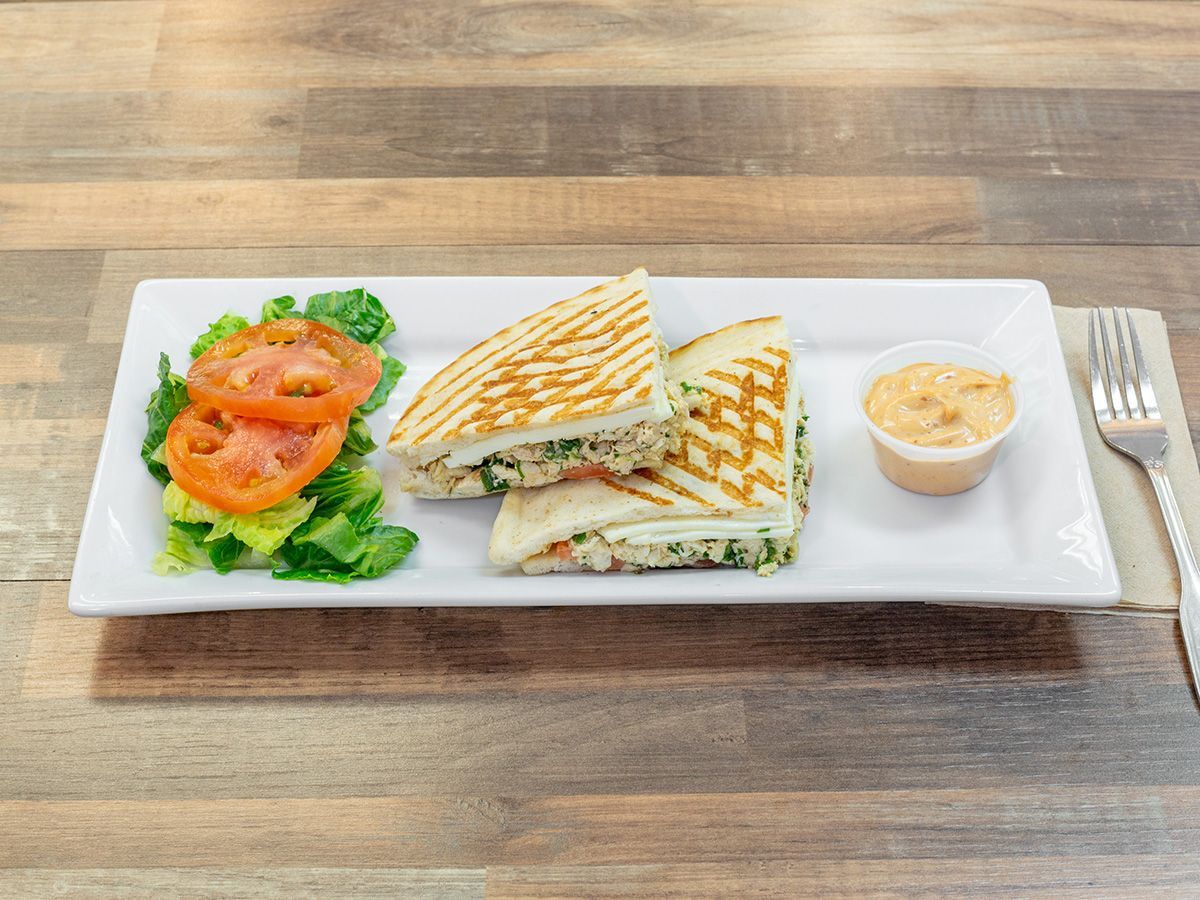 A white plate topped with a sandwich and a salad on a wooden table.