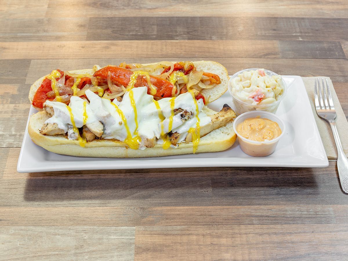 A sub sandwich with coleslaw and mustard on a white plate on a wooden table.
