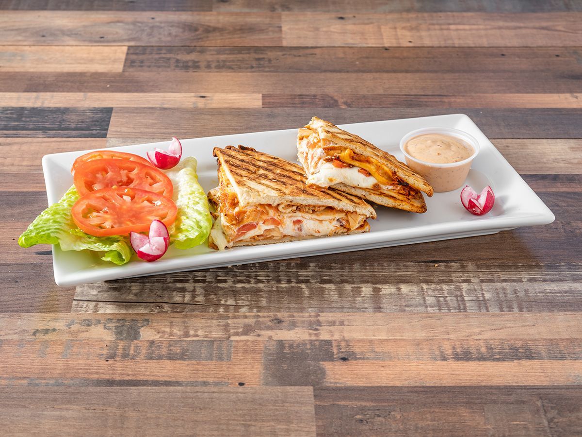 A white plate topped with sandwiches and vegetables on a wooden table.