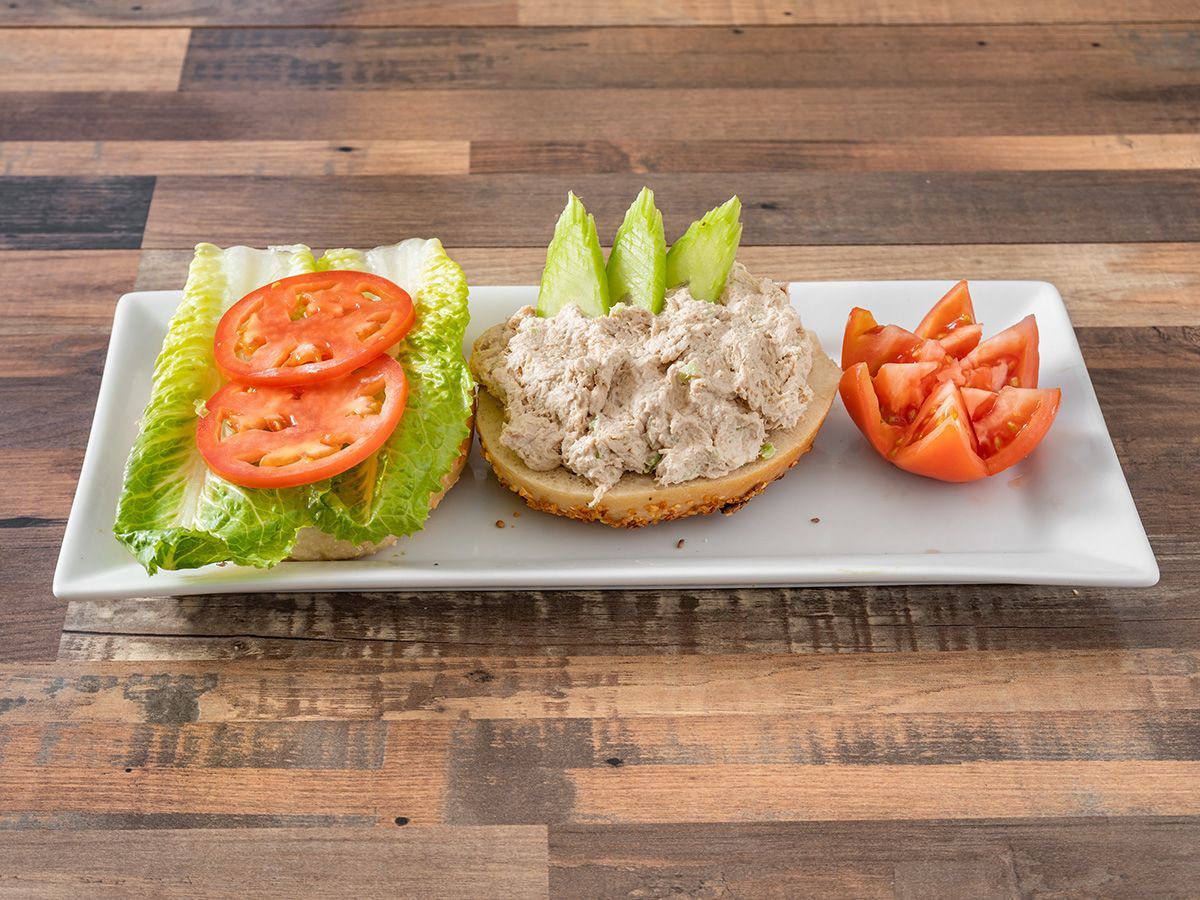A white plate topped with a sandwich, lettuce, tomatoes and cucumbers.