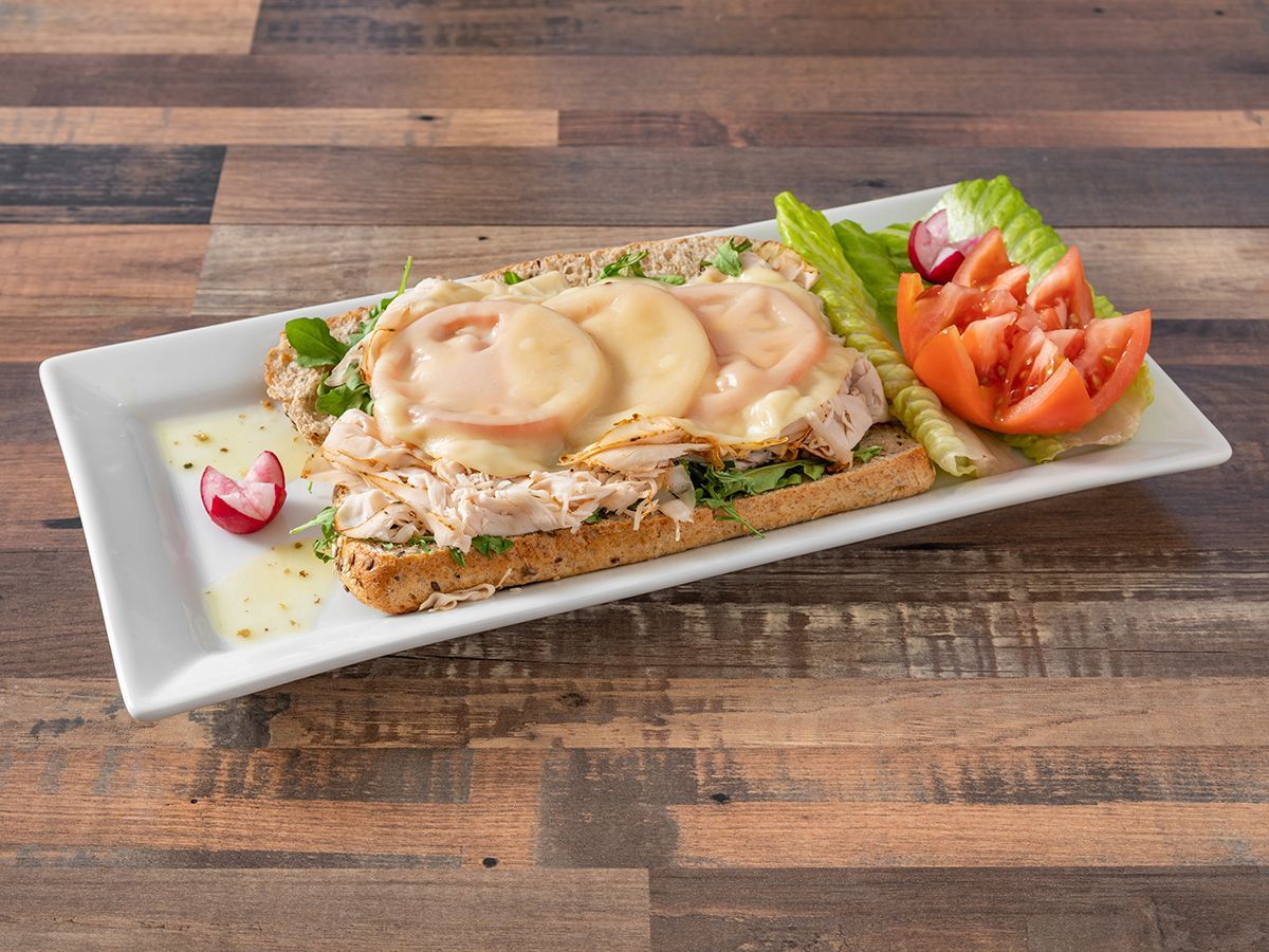 A white plate topped with a sandwich and vegetables on a wooden table.