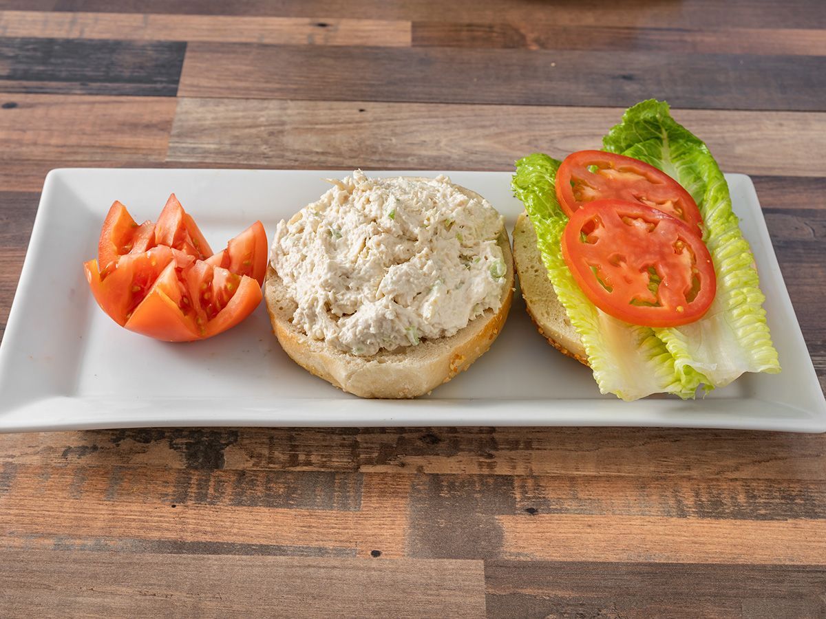 A white plate topped with a sandwich, lettuce and tomatoes on a wooden table.