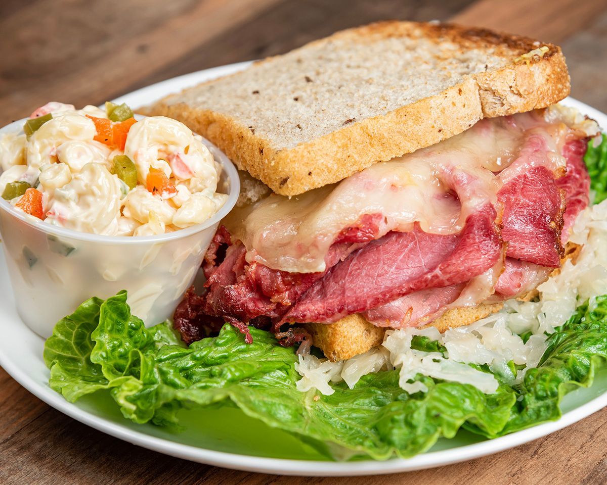 A corned beef sandwich on a plate with lettuce and coleslaw.