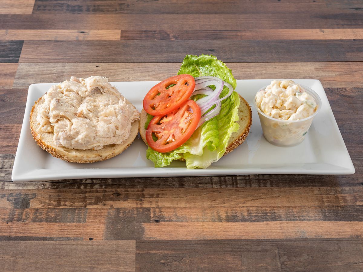 A sandwich with lettuce, tomatoes, onions and mayonnaise on a plate on a wooden table.