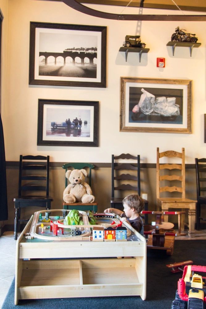 Child playing at a toy table in a cafe with framed photos on the wall
