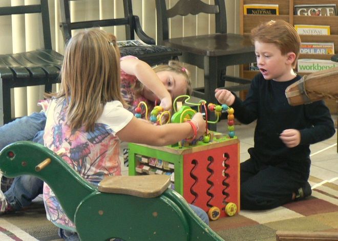 Two children playing with a colorful toy in a classroom play area