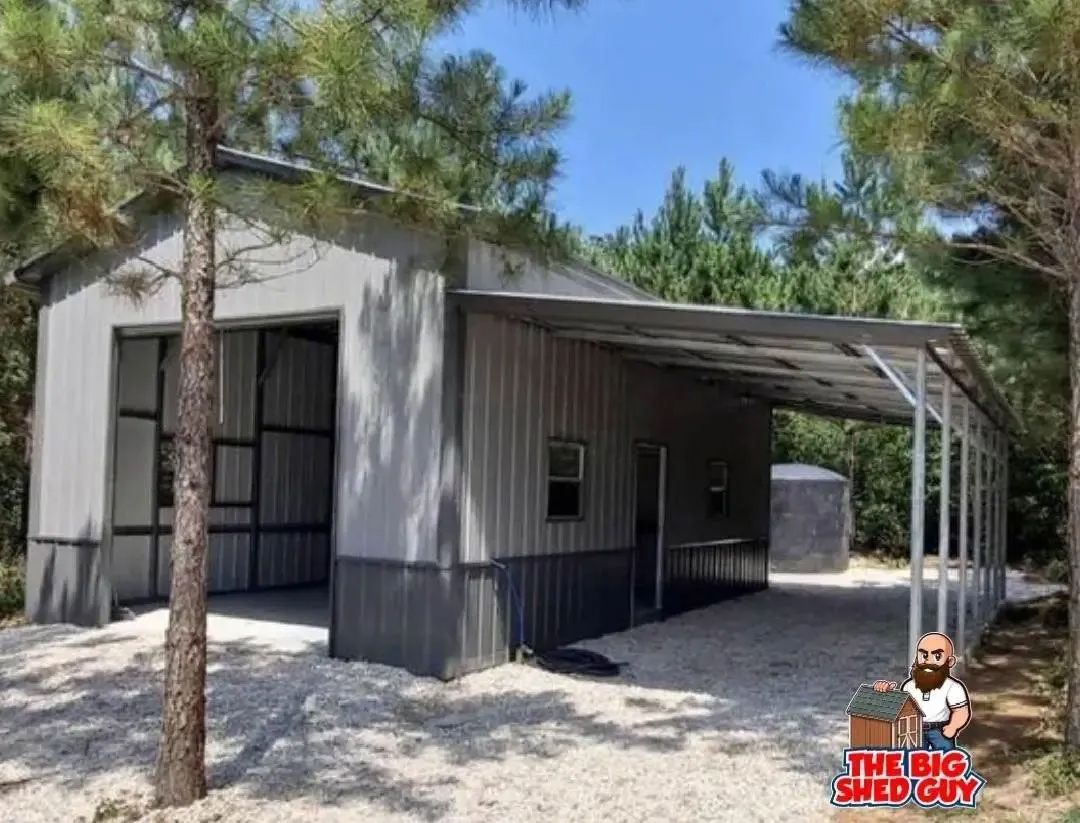 Gray metal building with attached carport in a wooded area.