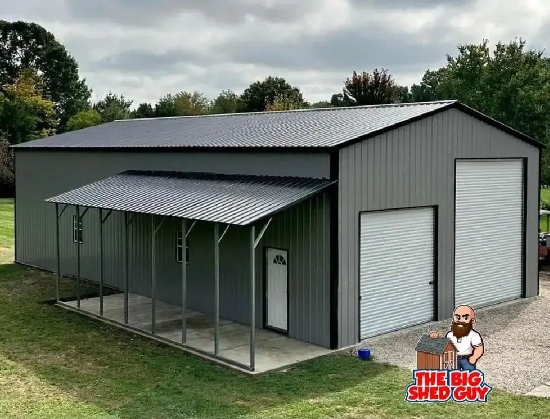 Gray metal shed with a porch and two garage doors on a grassy lot.