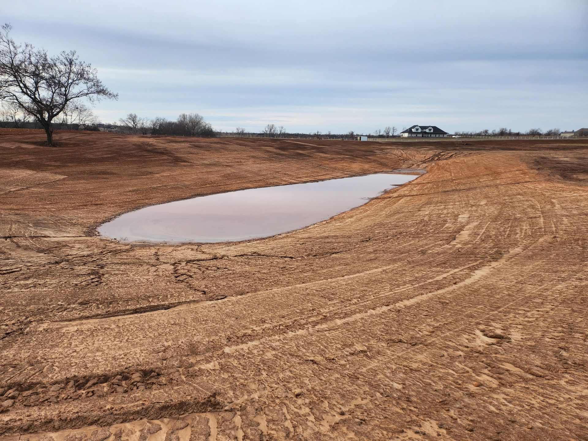 A small pond in the middle of a dirt field