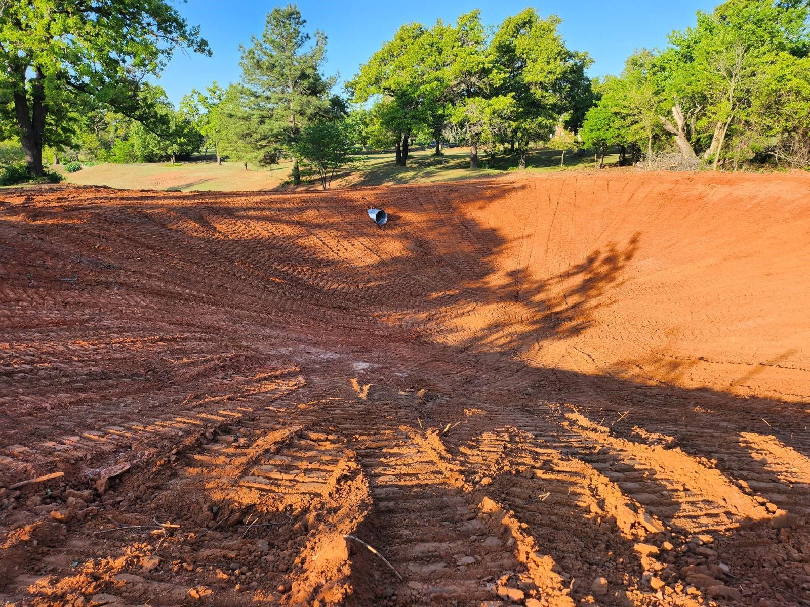A large pile of dirt with trees in the background