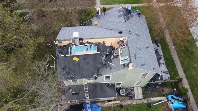 Aerial view of a house with a damaged roof and scattered debris after storm damage