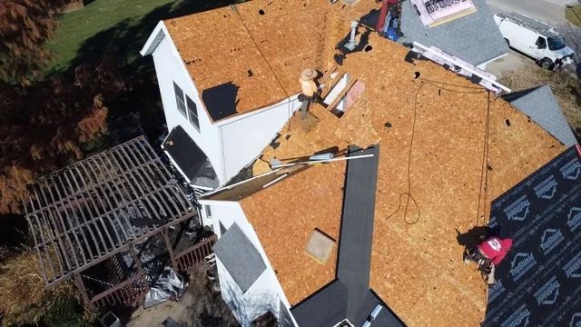 Aerial view of a house roof with storm damage and exposed sections near a damaged patio area