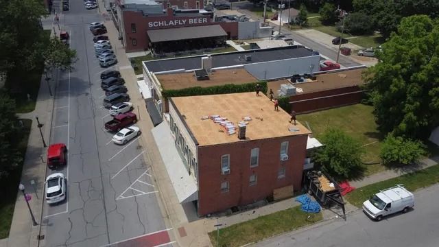 Aerial view of a brick building, parked cars, and a street in a small urban neighborhood.