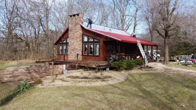 Rustic cabin with red roof and stone chimney in a wooded clearing