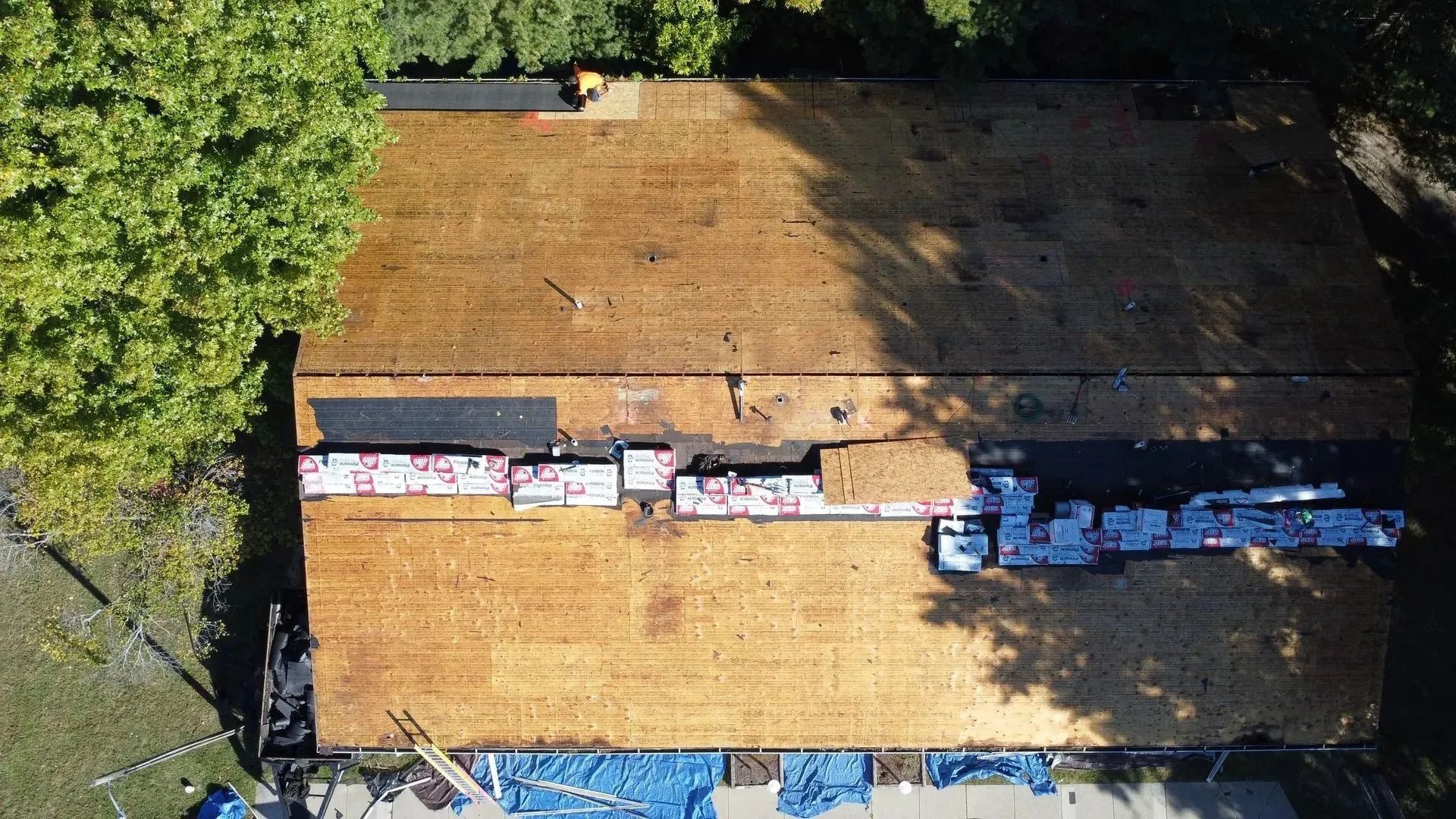 Aerial view of a roof with weathered shingles and a strip of exposed underlayment near the center.