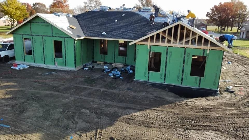 Partially framed green house under construction with workers on the roof and in the yard