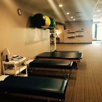 Therapy room with treatment tables, exercise equipment, and neutral decor.