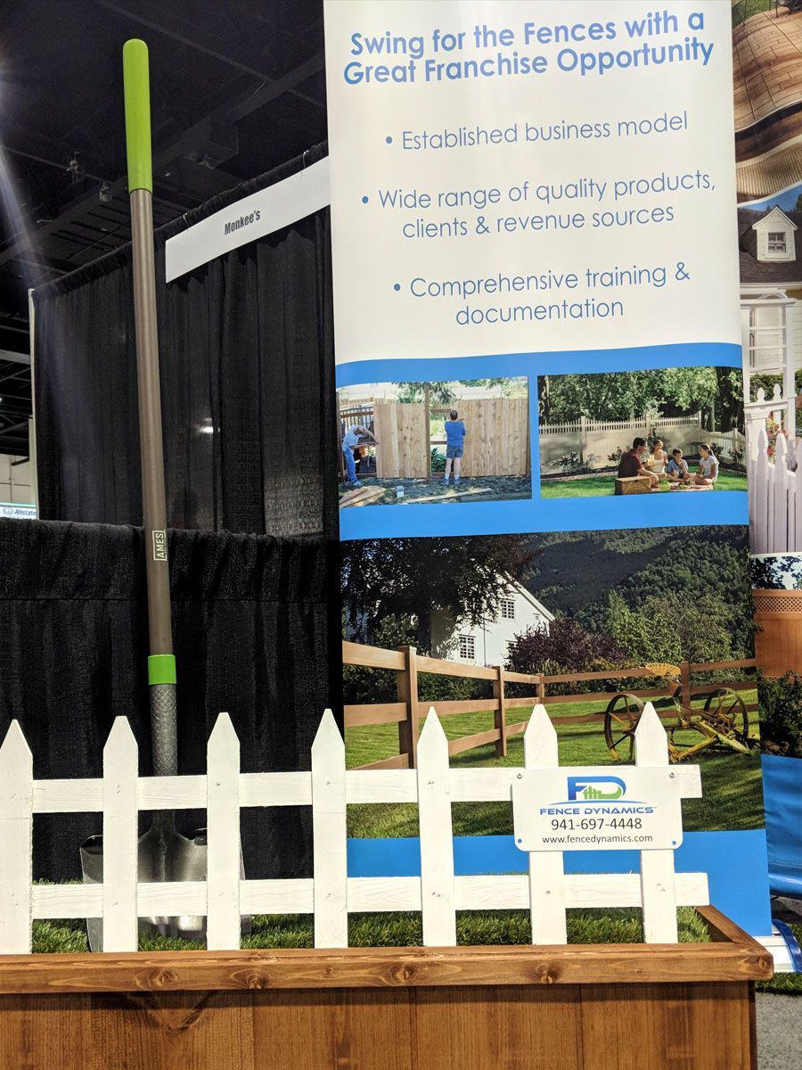 Banner for a “Swing for the Fences” Great French Opportunity event behind a white picket fence