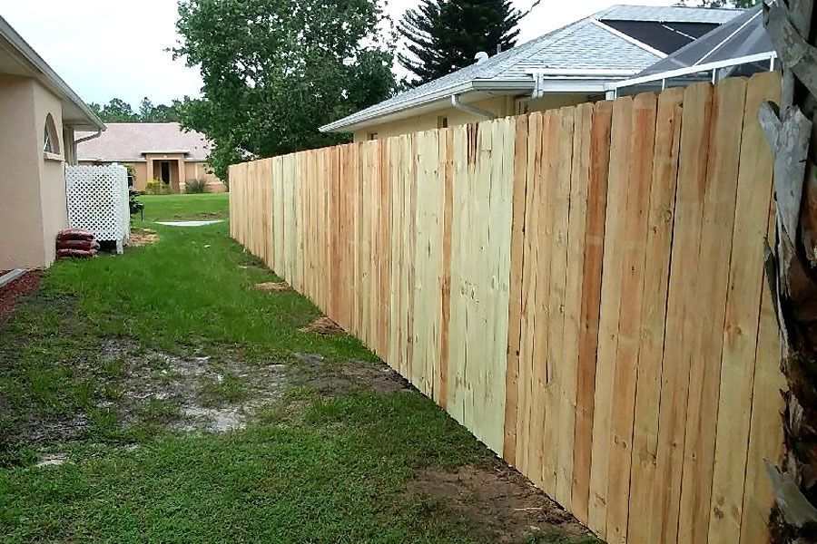 New wooden privacy fence along a grassy side yard beside a house