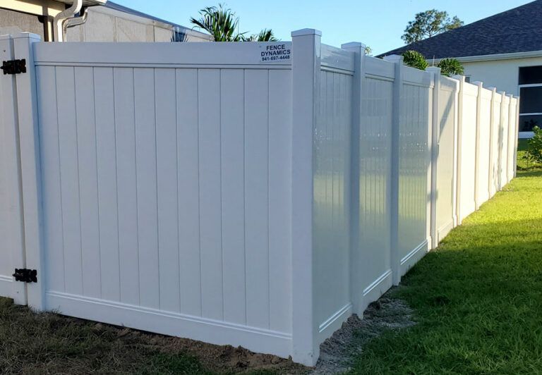White vinyl privacy fence with gated corner in a suburban yard