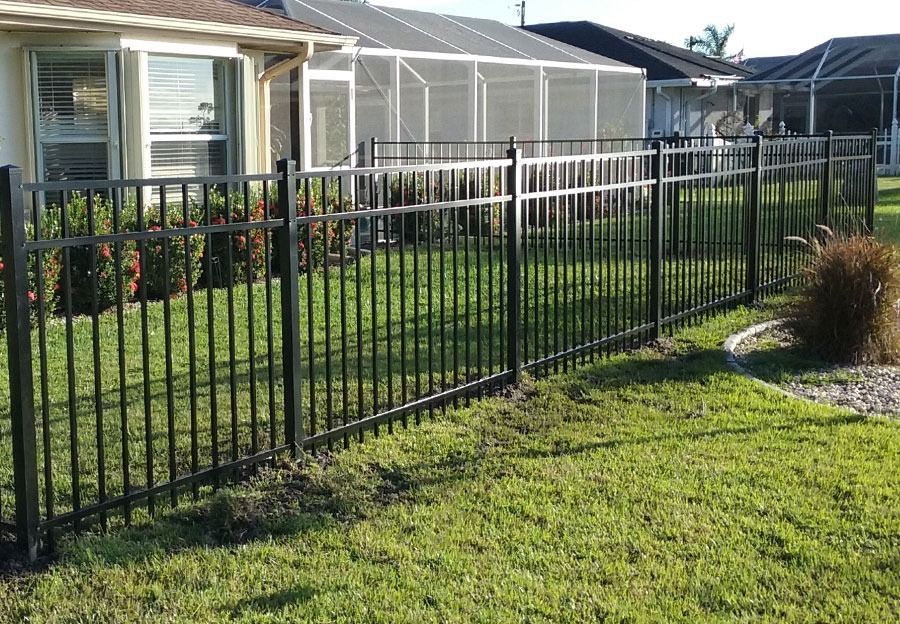 Black metal fence along a grassy yard beside a house with screened porch.