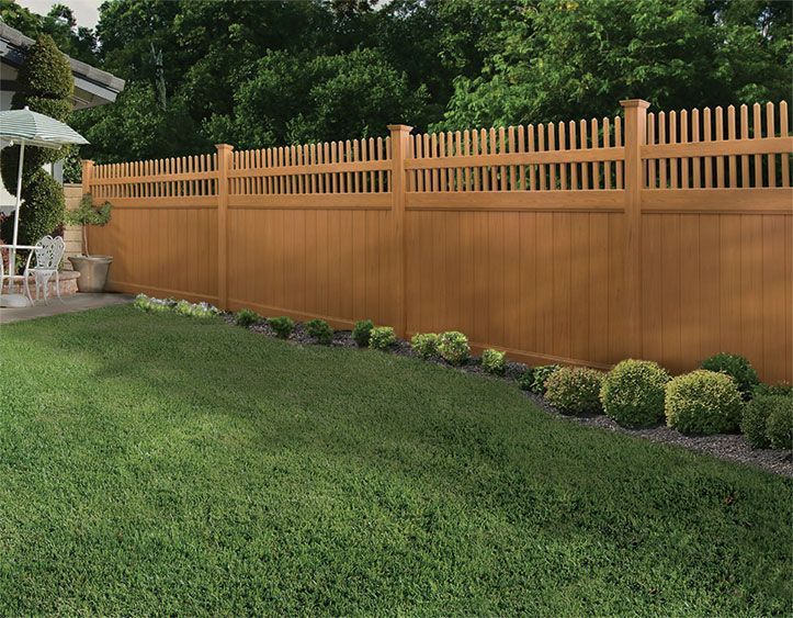 Backyard lawn with a wooden privacy fence and neatly trimmed shrubs along the edge