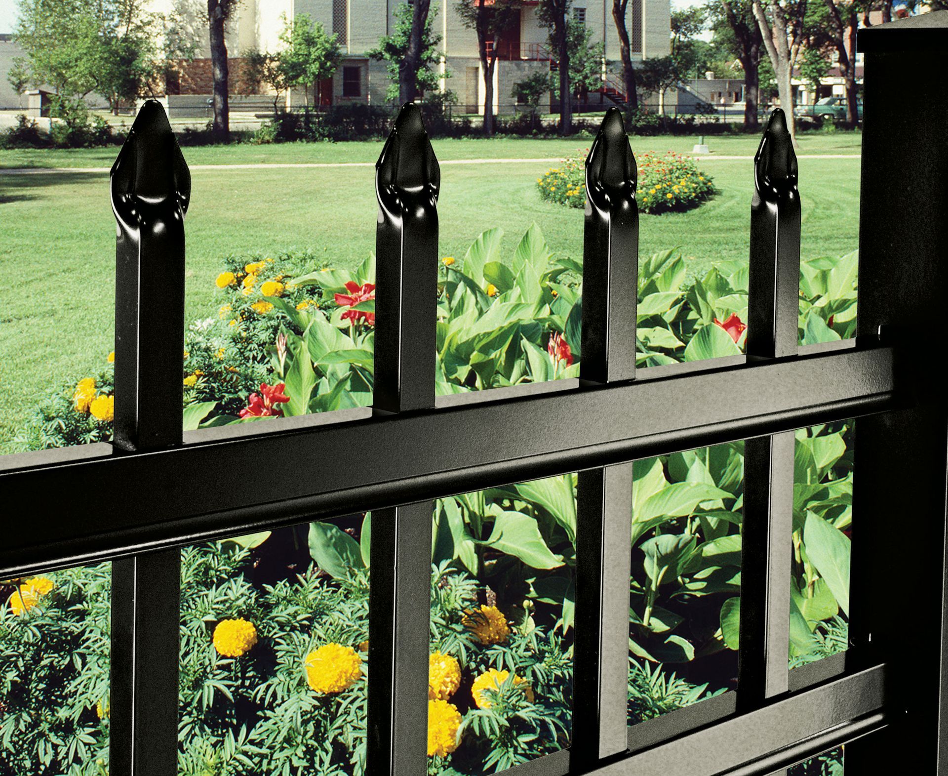 Black iron fence in front of a colorful flower garden in a park