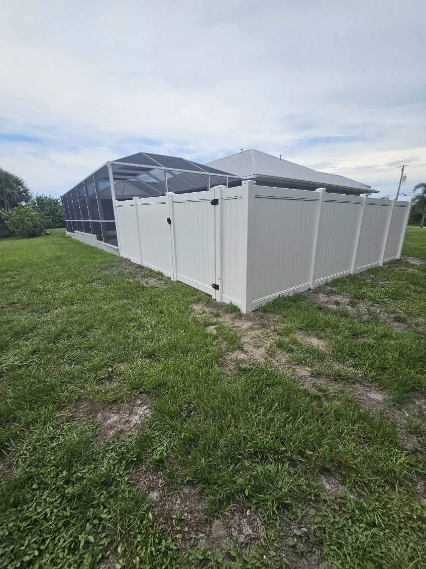Large white temporary fencing around a dark tent on grassy ground under a cloudy sky