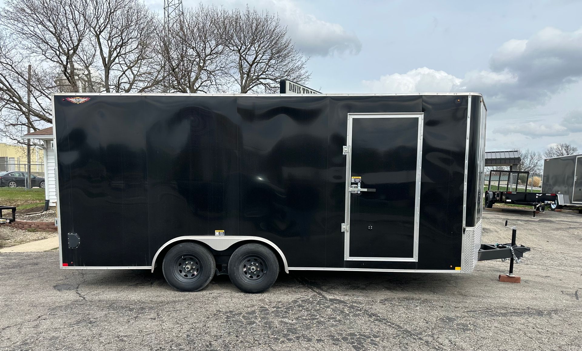 A black and silver trailer is parked on the side of the road.