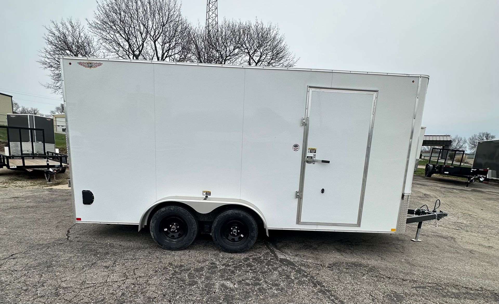 A trailer is parked in a gravel lot in front of a building.