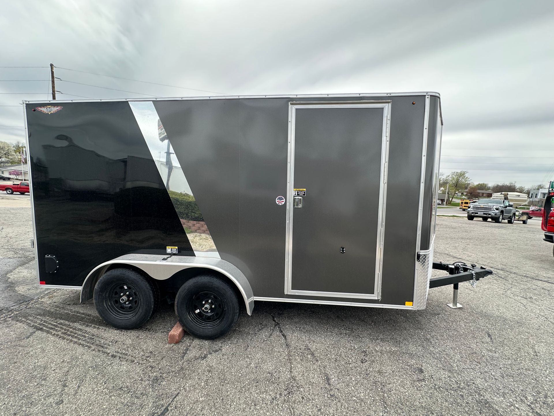 A gray trailer is parked in a gravel lot in front of a building.