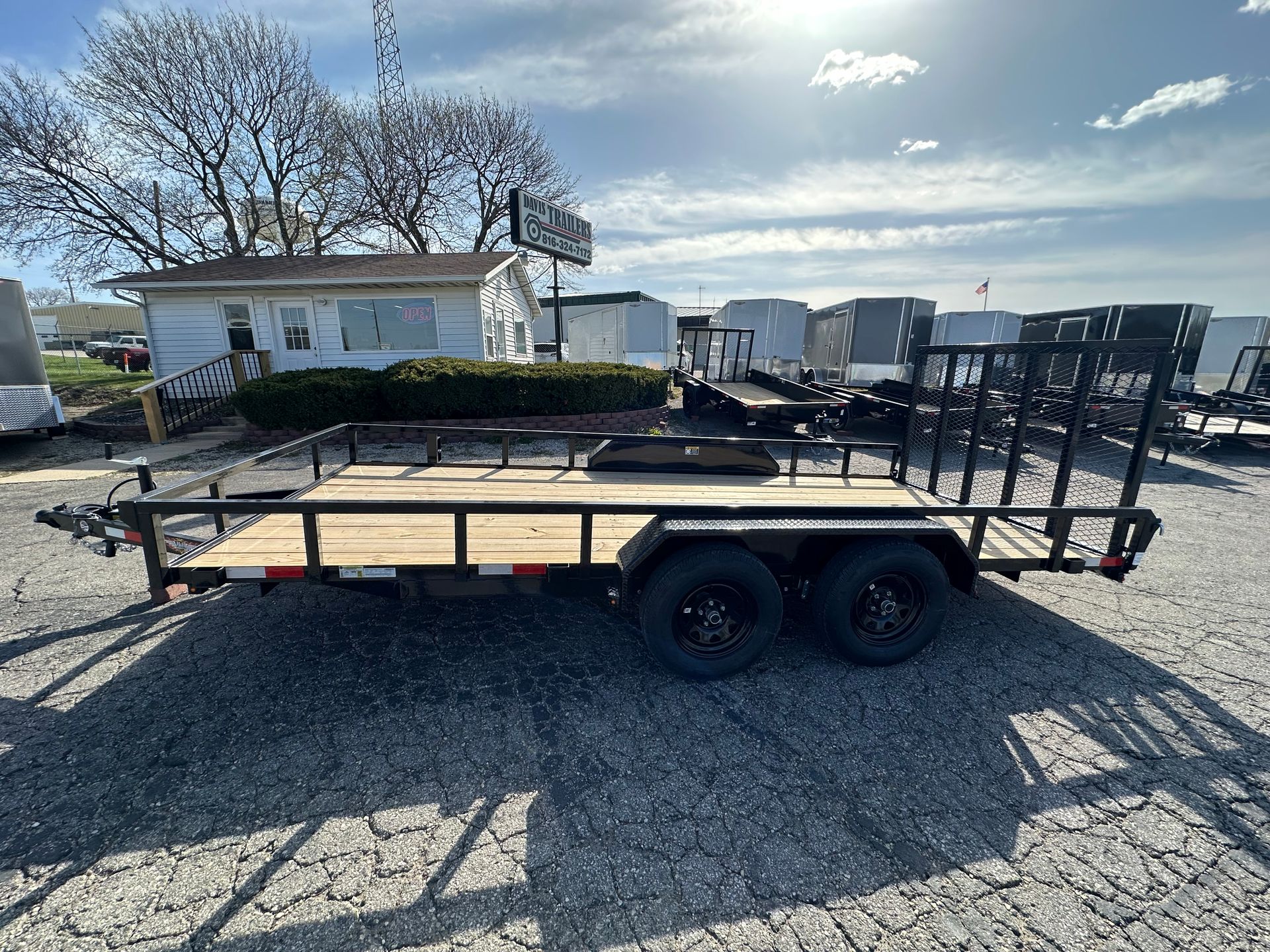 A trailer is parked in a grassy field next to a road.