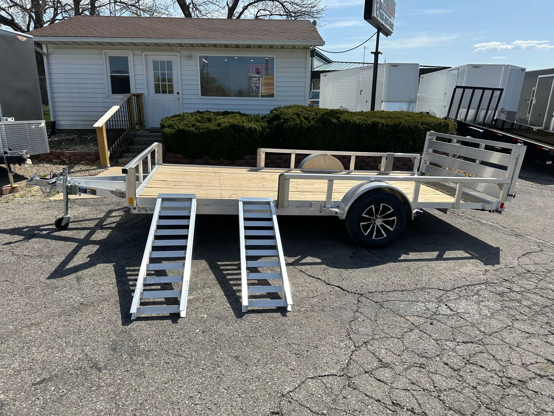 A trailer with a ramp attached to it is parked in a grassy field.