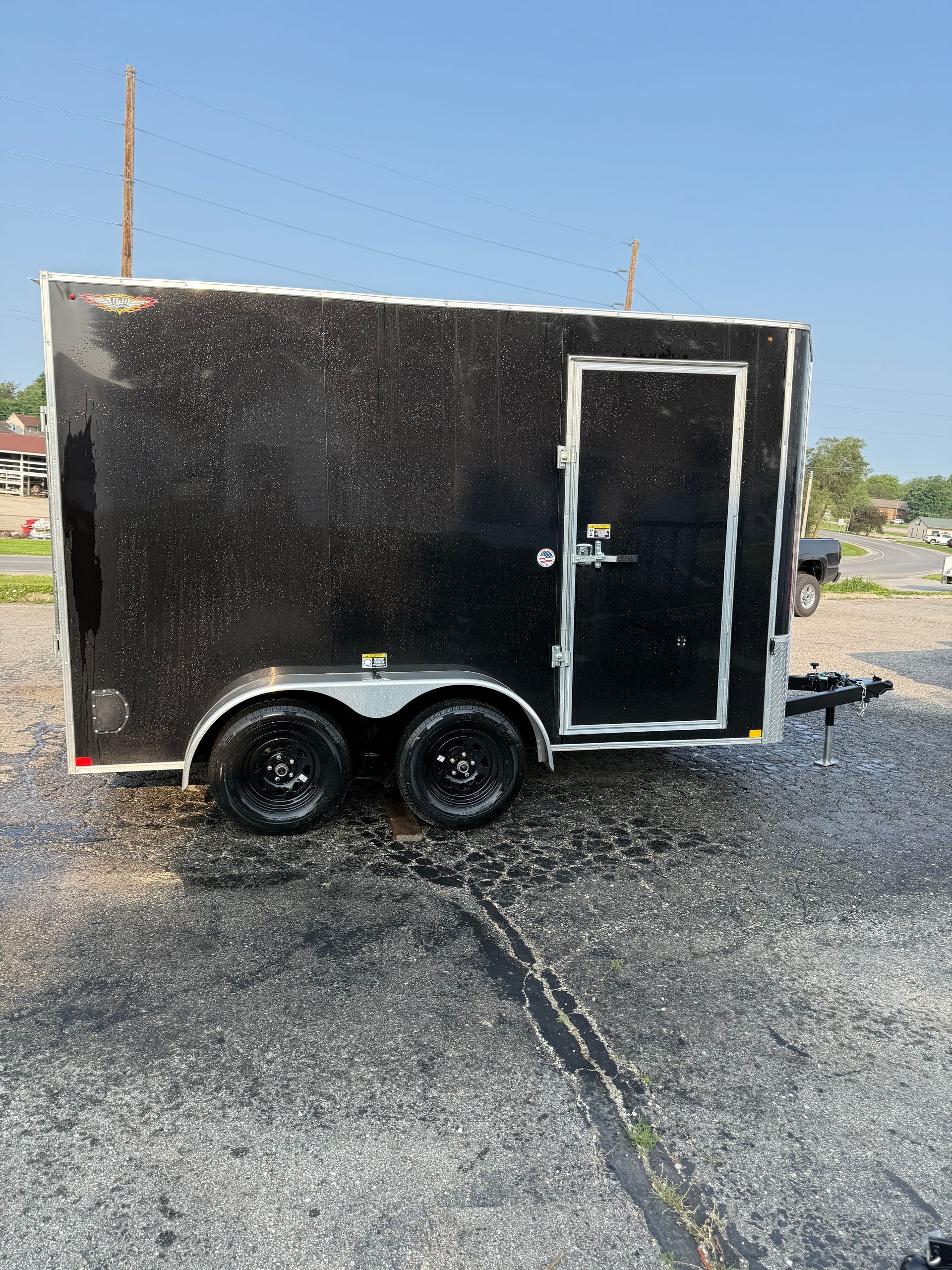 A trailer is parked in a gravel lot in front of a building.