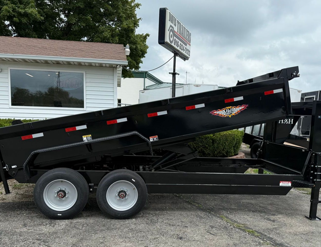 A dump trailer is parked in a gravel lot.