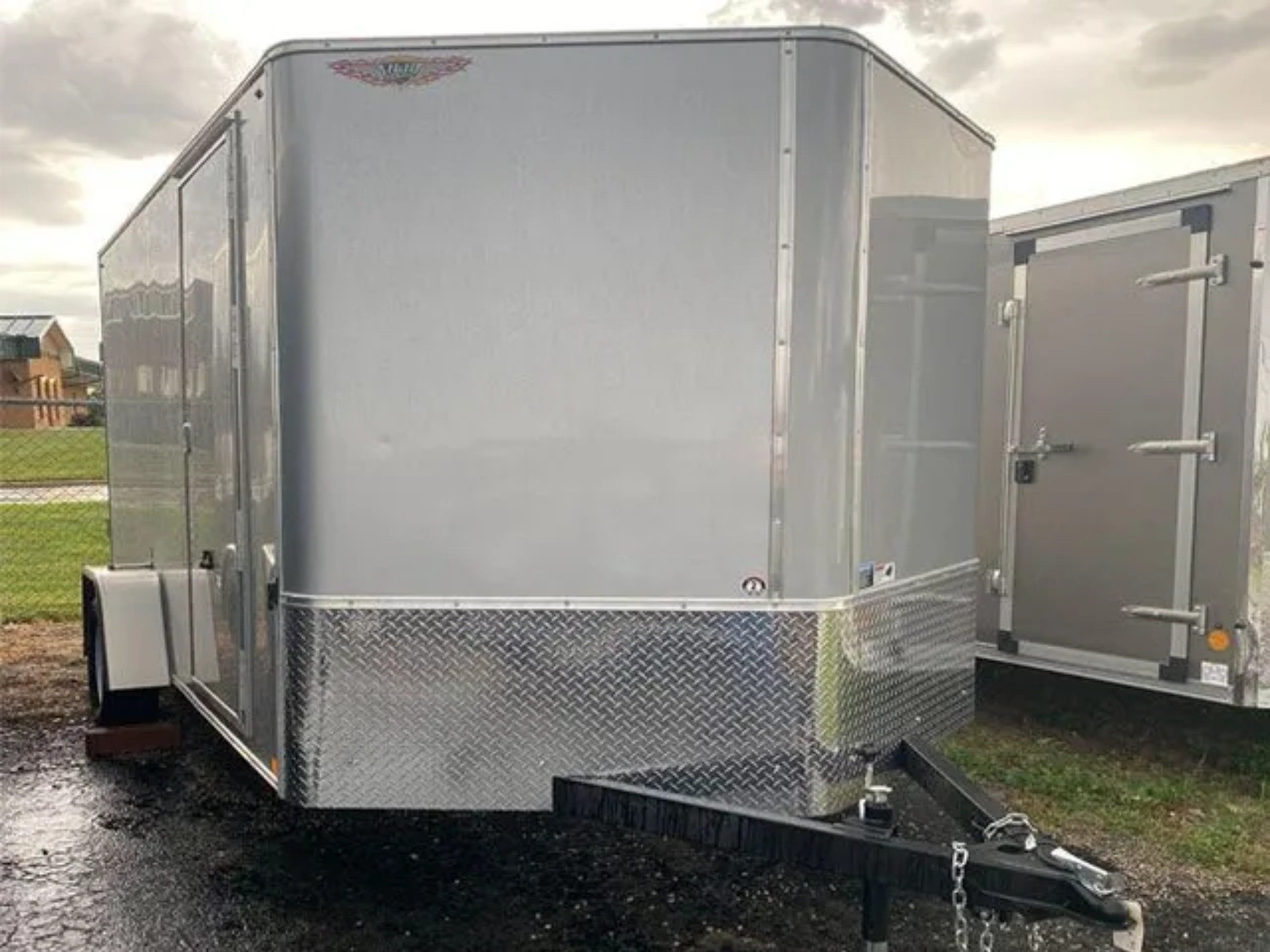 A silver trailer is parked on the side of the road.