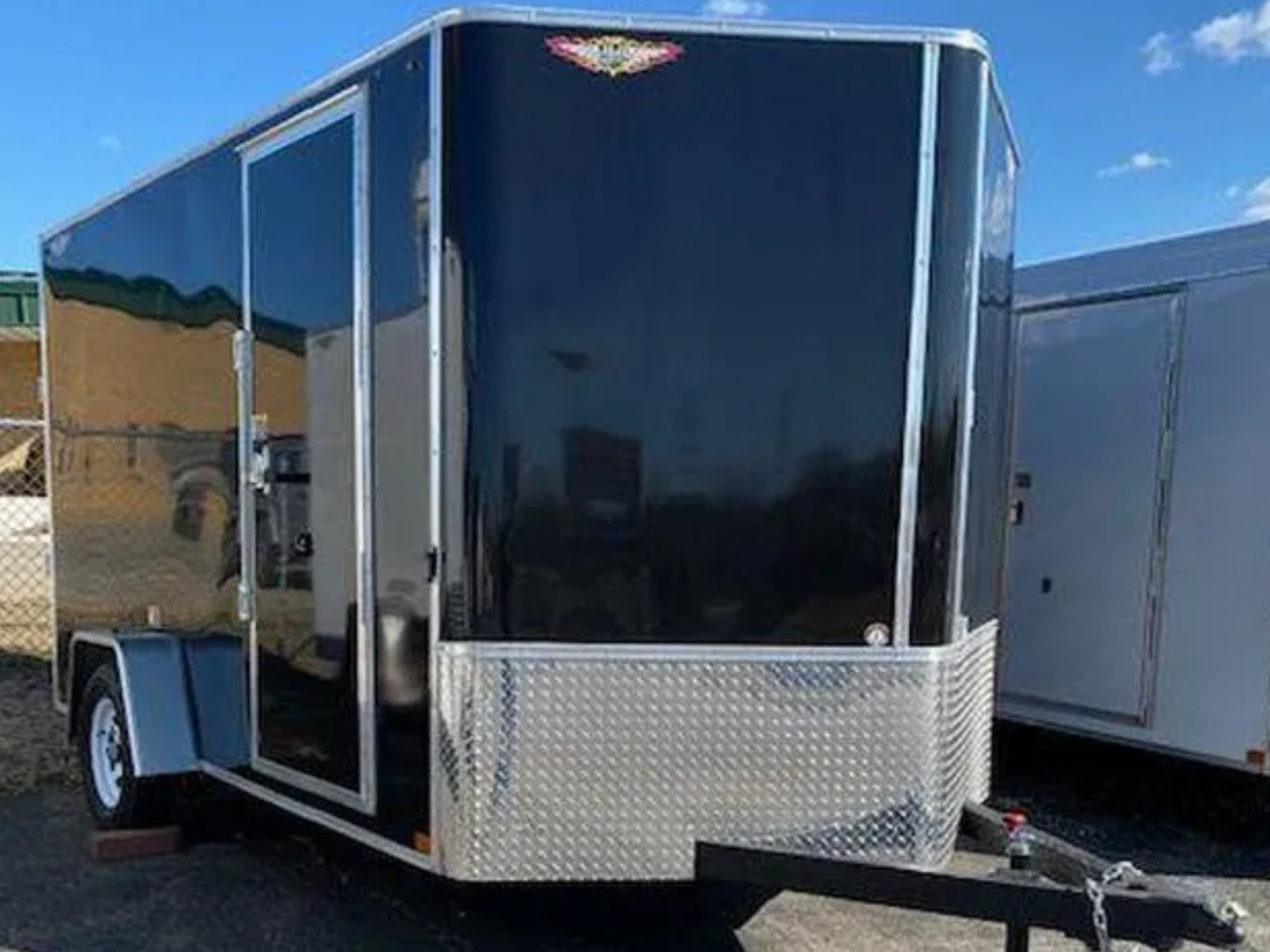 A black and silver trailer is parked in a parking lot.