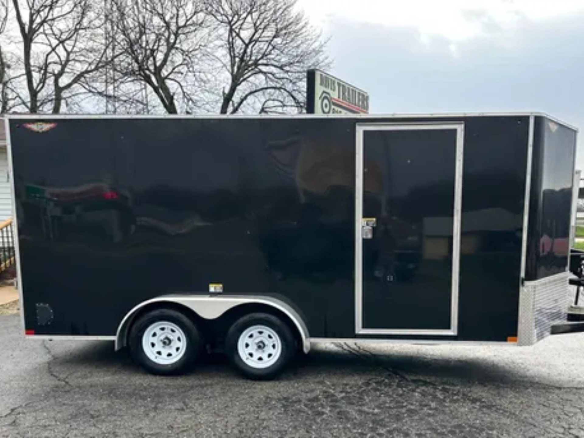 A black trailer is parked on the side of the road.