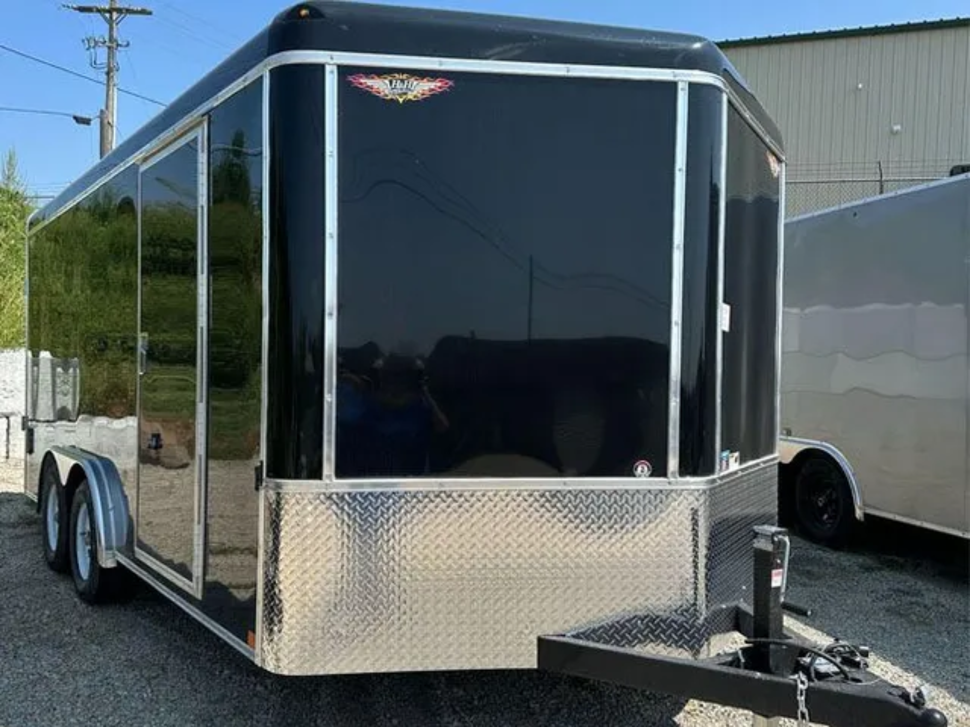 A black and silver trailer is parked on the side of the road.