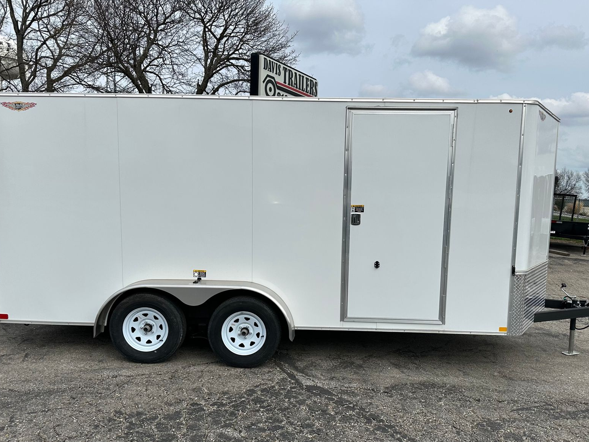 A dump trailer is parked in front of a white building.
