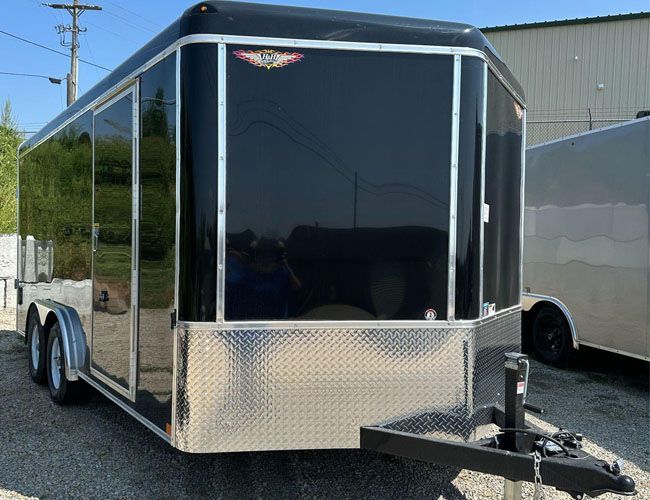 A black and silver trailer is parked on the side of the road.