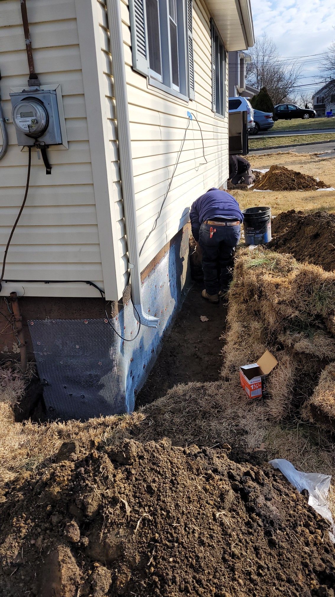 A man is digging a hole in front of a house.