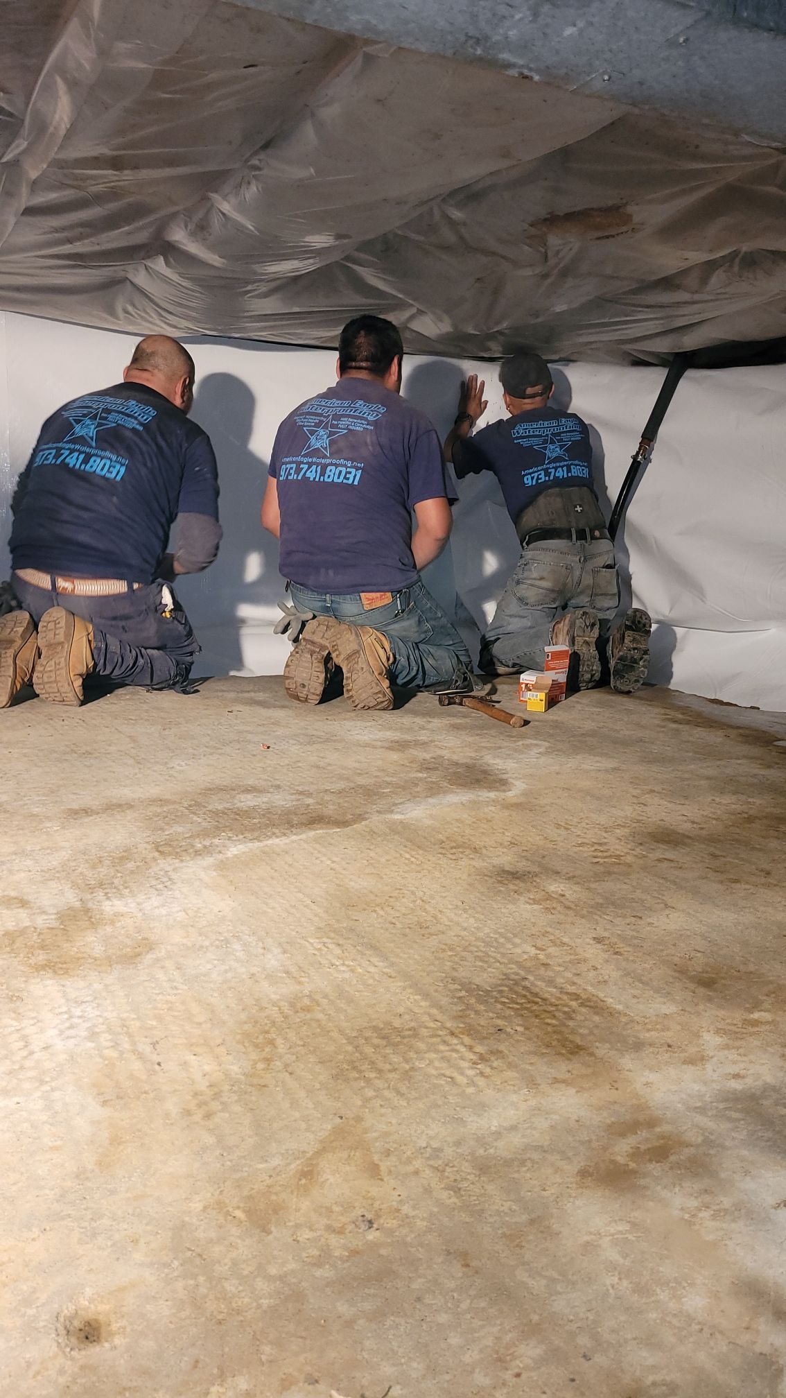 A group of men are kneeling down in a basement.